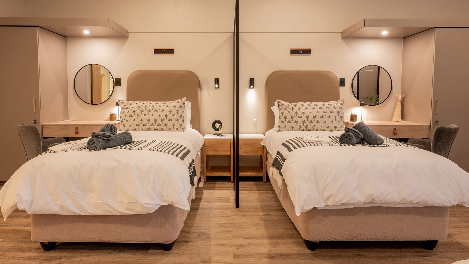 Twin guest room at The Ark with upholstered headboards, round mirrors and patterned cushions