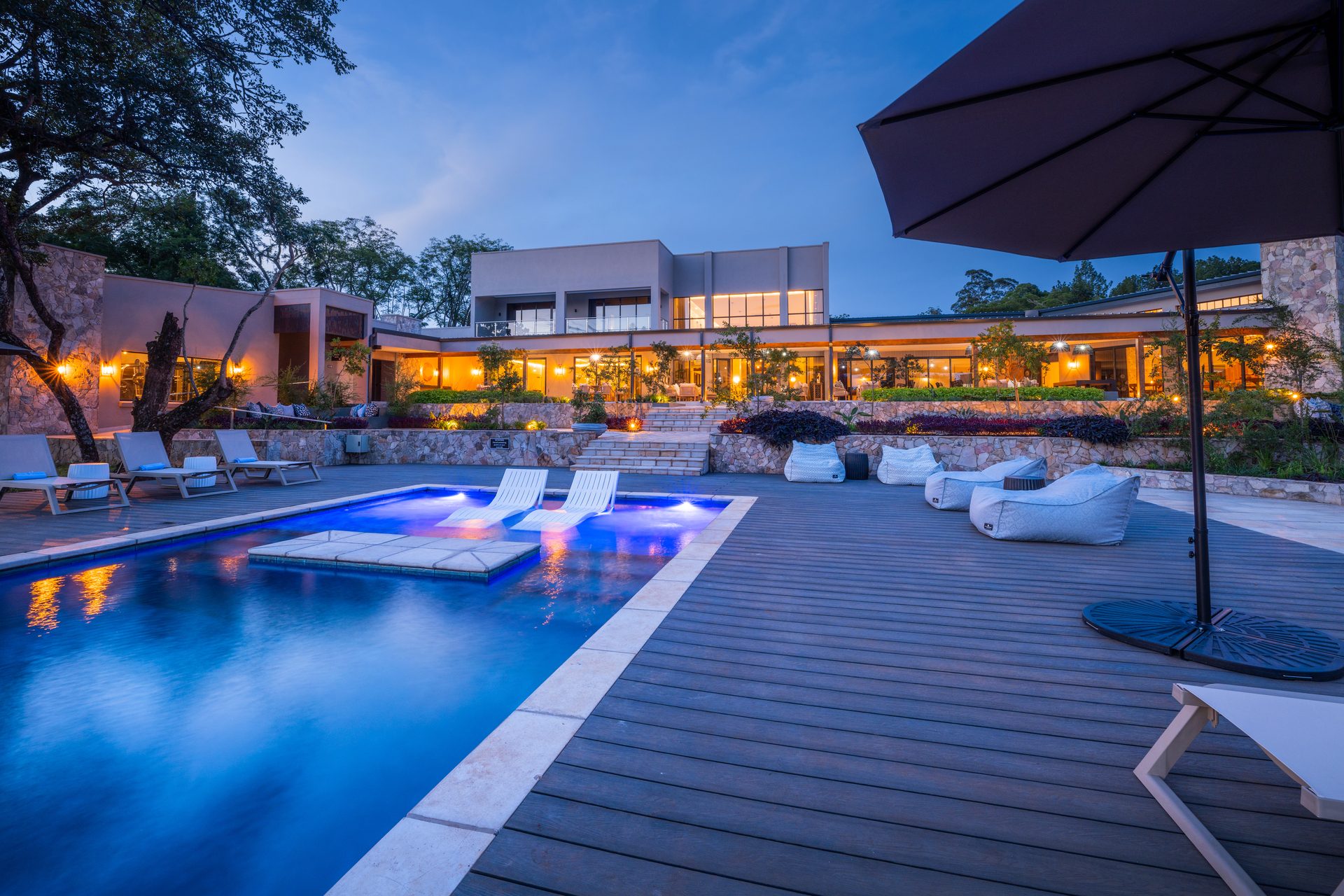 Pool terrace at The Ark at blue hour, loungers and parasol against the lit facade