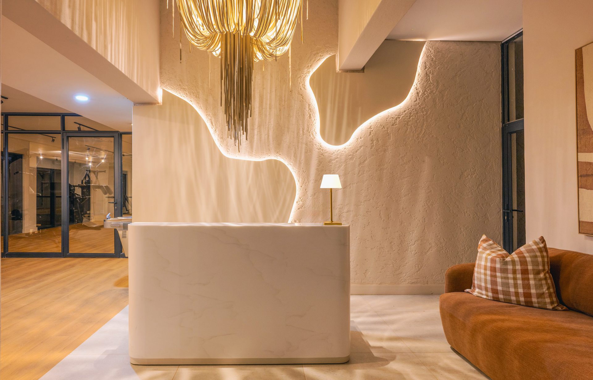 Lounge at The Ark with a sculptural fringe pendant and a curved light line carved into a textured wall
