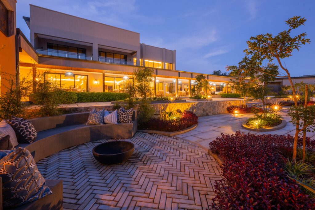 Courtyard at The Ark at dusk, with a fire pit, brick paving and layered planting