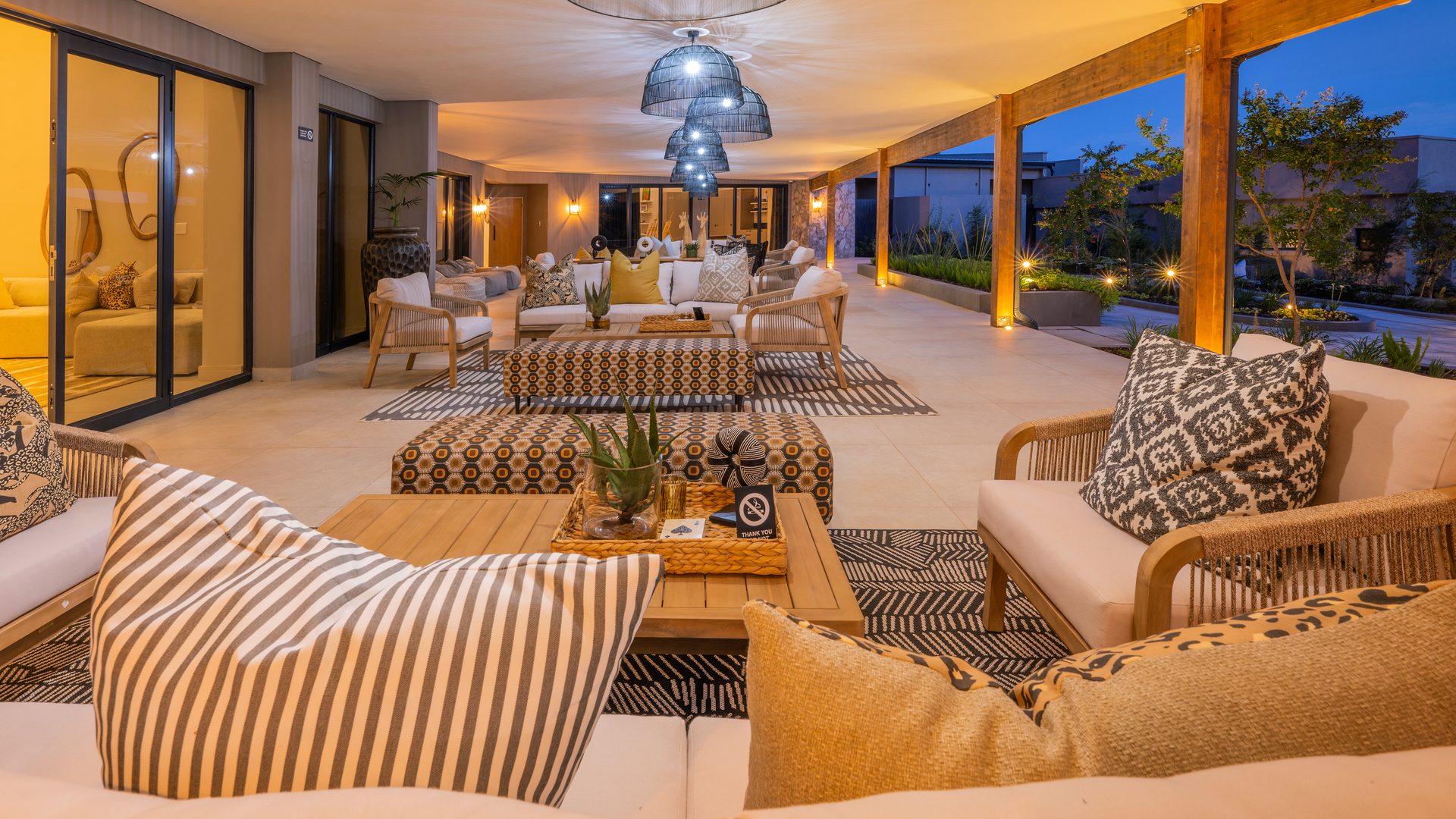 Covered terrace at The Ark with rattan seating and striped upholstery at dusk