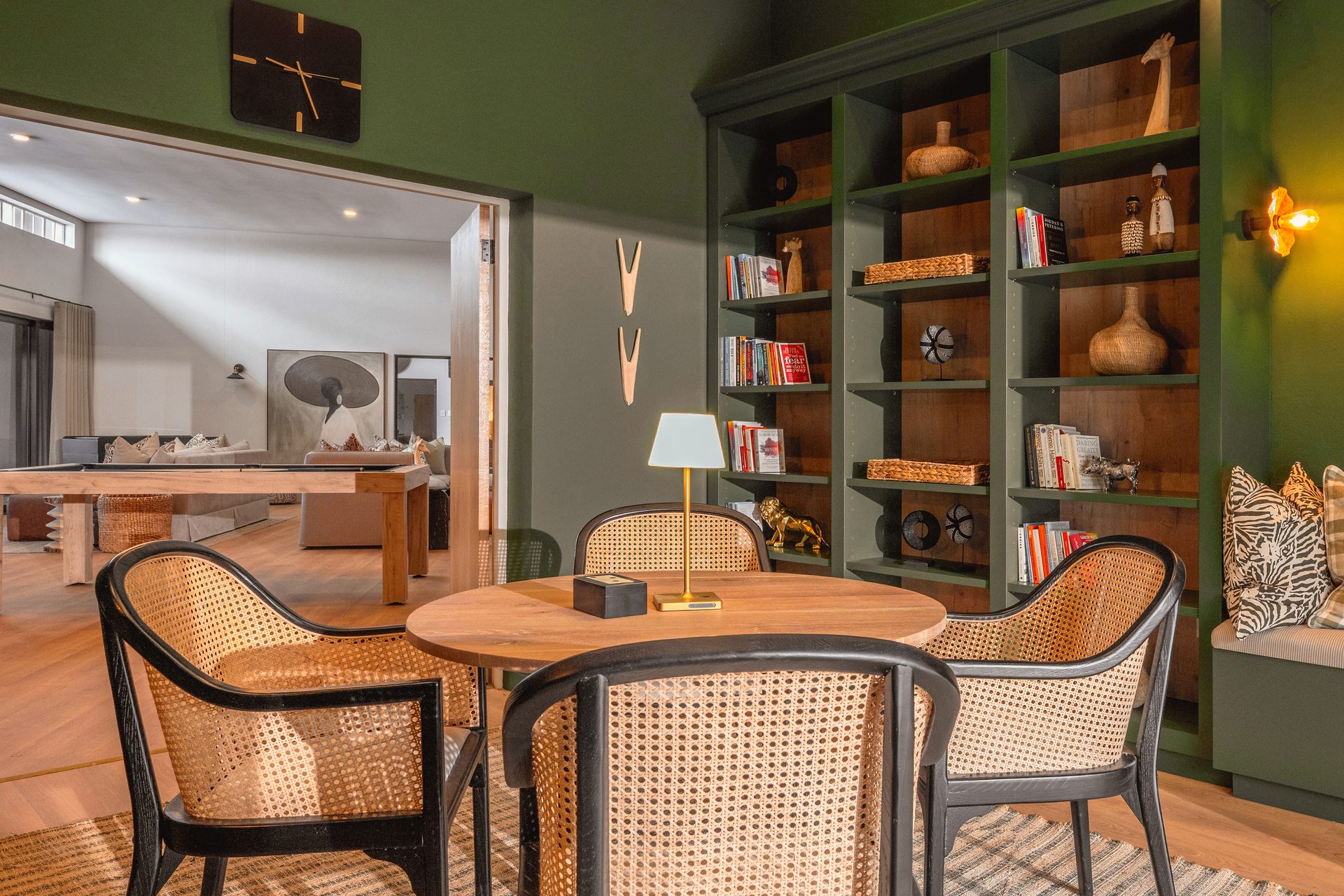 Library at The Ark with deep green joinery, cane chairs and warm shelf lighting